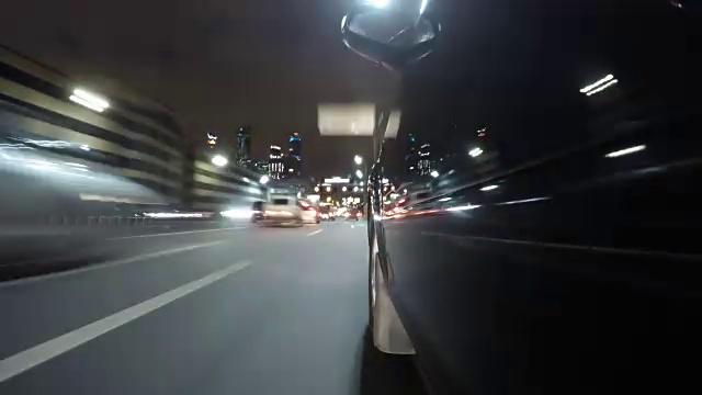 快速城市驾驶夜间道路POV通过城市在夜间时间推移左侧的汽车。低角度的观点