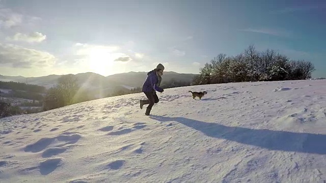 活跃的比格犬和它的女主人在雪山田野边奔跑的慢镜头