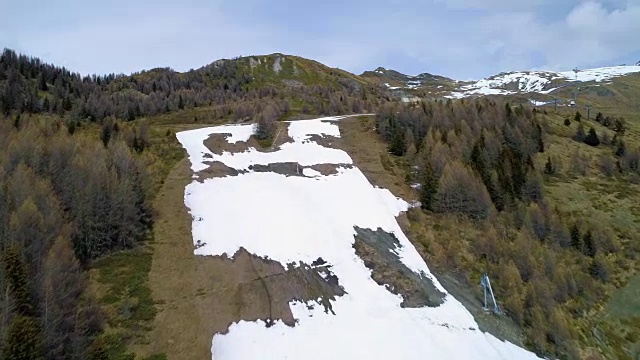 继续向前走，发现秋季的松林和高山雪道。秋天阿尔卑斯户外自然景观山野生空中建立。4k无人机飞行建立镜头