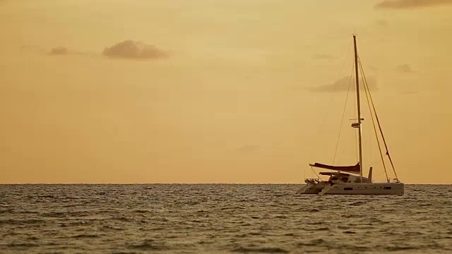 奈罕海滩上的日落。游艇在波浪中摇摆。云景在橙色日落背景