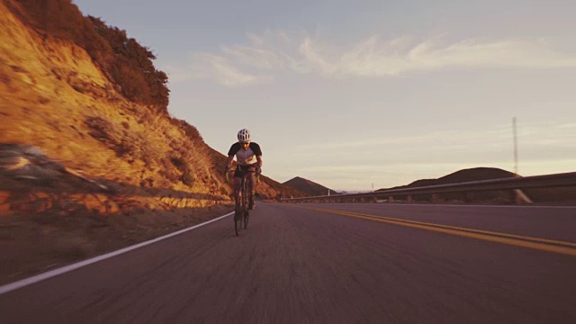 详情图-年轻的健康男子在公路上骑自行车，在户外在日落下山比赛