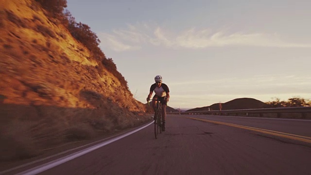 详情图-年轻的健康男子在公路上骑自行车，在户外在日落下山比赛