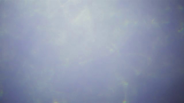 黑色背景上细微的漏光，移动的镜头光晕。蓝色柔和的颜色。移动凉爽的蓝色纹理创意海底效果