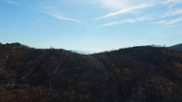 一场大火后，在山坡上燃烧的森林上空的空中飞行
