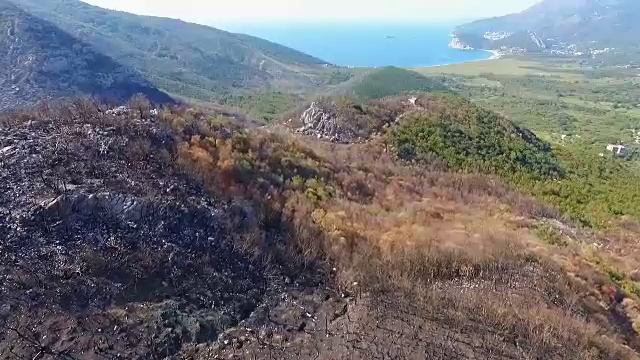 一场大火后，在山坡上燃烧的森林上空的空中飞行