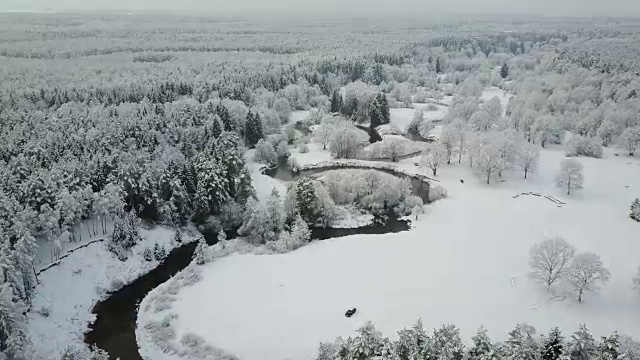 4 k。在冰冻森林中蜿蜒的河流上空低空飞行。鸟瞰图美丽的冬季山谷