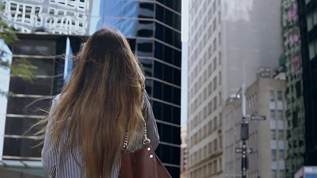 在纽约金融区工作的年轻女商人用手机聊天的背影。慢动作