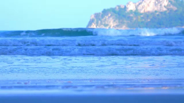 沙滩上的沙子和海浪绿色的海或海洋在蓝色的绿色的天空或蔚蓝的天空。从沙滩上看到美丽的海景。