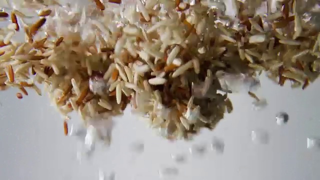 詳情圖-棕色和紅色的米粒落入沸水中。宏觀視圖