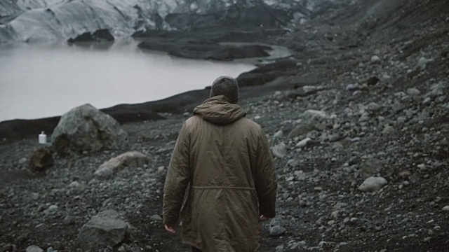 年轻男子独自走在冰湖上的背影。在冰岛冰川附近的火山中徒步旅行的男性