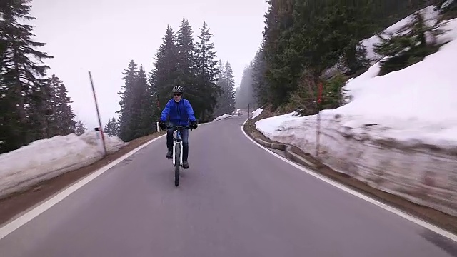 老年人在冬季的山路上骑车