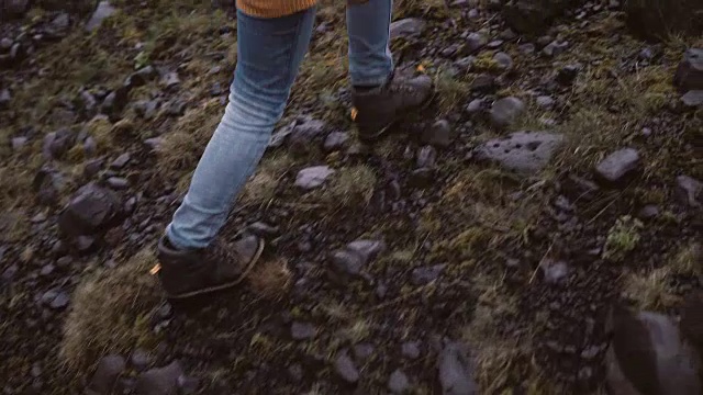 年轻女子徒步在岩石山的后视图。独自探索冰岛的旅行女性，徒步穿越沼泽