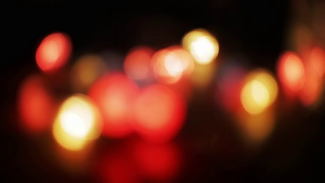 抽象散焦彩色闪烁灯。黑色背景上的圣诞和新年花环。Loopable