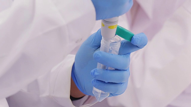 生物技术专家从玻璃烧瓶中提取液体样本进行近距离测试