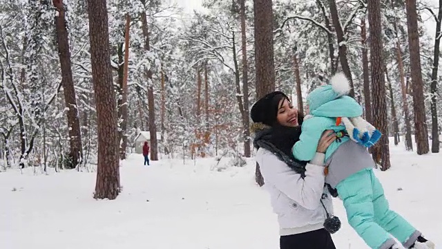 快乐的女人和孩子在冬天的公园玩雪。慢镜头般的假期