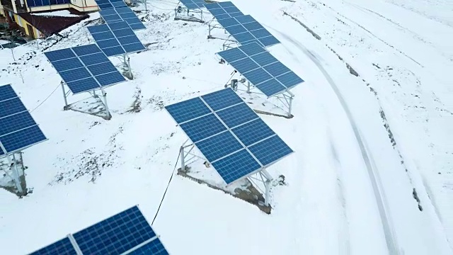 在小型太阳能发电厂，成排的积雪覆盖着太阳能电池板。