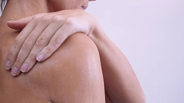 肩部和女性背部身体乳液蔓延缓慢动作特写