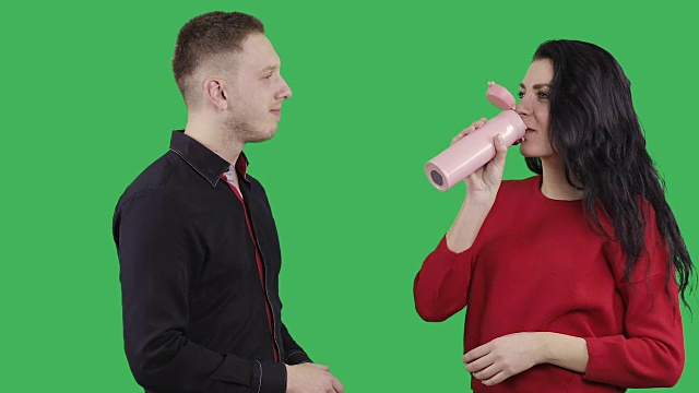 一个穿着黑色衬衫的年轻人正在用热茶杯给一个漂亮的黑发女子倒热茶。