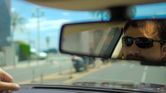 在行驶中的汽车、交通中，太阳镜在后视镜中的男性脸的反射