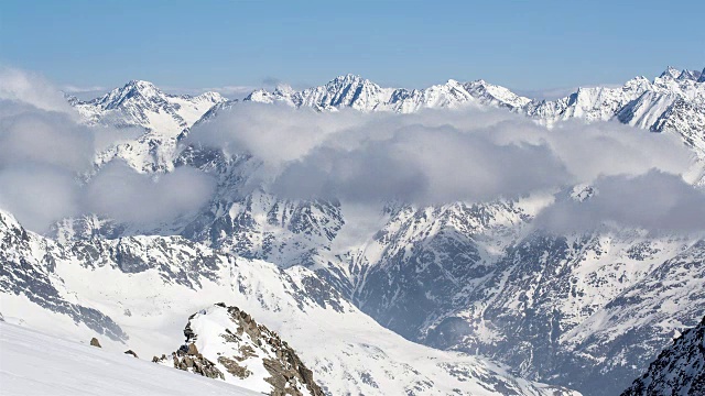 阳光明媚的一天在冬天的低云雪山山脉的时间流逝