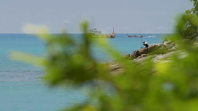 2012年11月18日，泰国普吉岛。人们在岸边钓鱼。渔船在波浪上摇摆