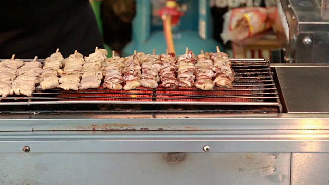 街头小吃摊贩在烤架上翻动各种肉串