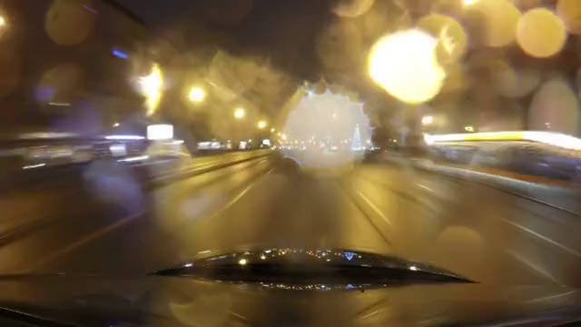 快速城市行驶夜间道路POV时间推移的挡风玻璃和车罩，雨夜，雨滴在玻璃上