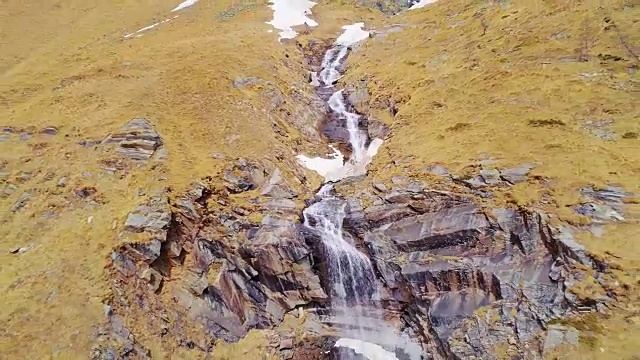 空中飞行向后移动远离瀑布，在黄山边瀑布建立。户外高山雪景是秋冬野外自然景观。4k无人机飞行建立镜头