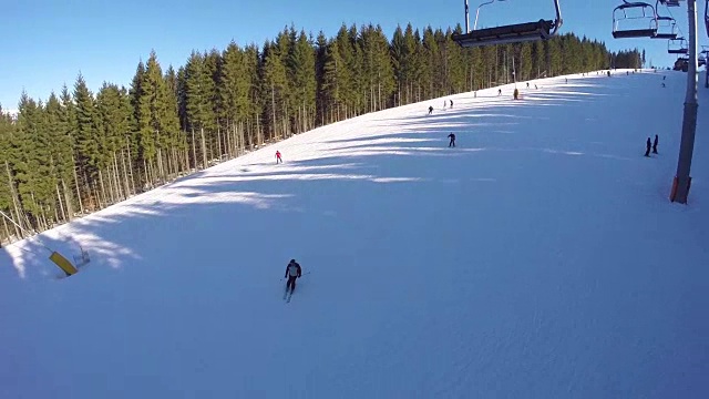 滑雪缆车把人们抬上山。滑雪者从多雪的山上下来。人们在滑雪，山坡上有高高的云杉