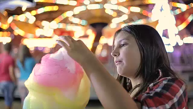 十几岁的女孩在游乐园吃棉花糖