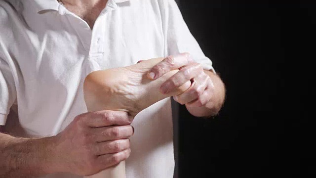 详情图-健康足部按摩。整骨医生做推拿的特写。男人用手按摩女人。水疗中心的概念