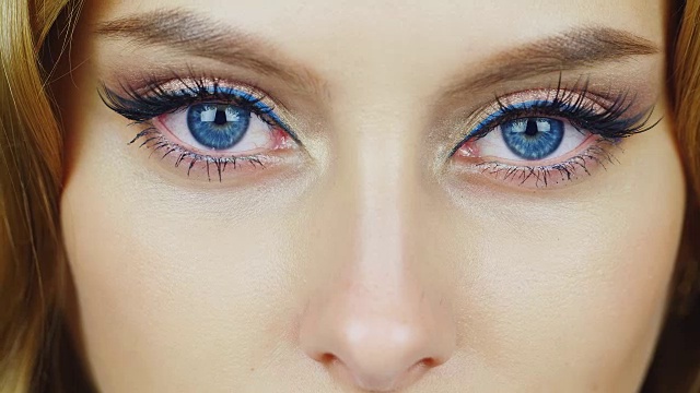 一个年轻女人看着摄像机的眼睛。富有表现力的蓝眼睛
