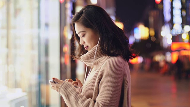 详情图-年轻的亚洲女人晚上在街上用智能手机