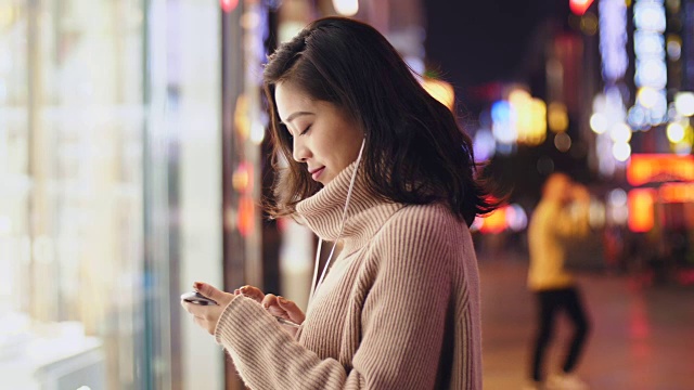 详情图-年轻的亚洲女人晚上在街上用智能手机