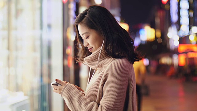 详情图-年轻的亚洲女人晚上在街上用智能手机