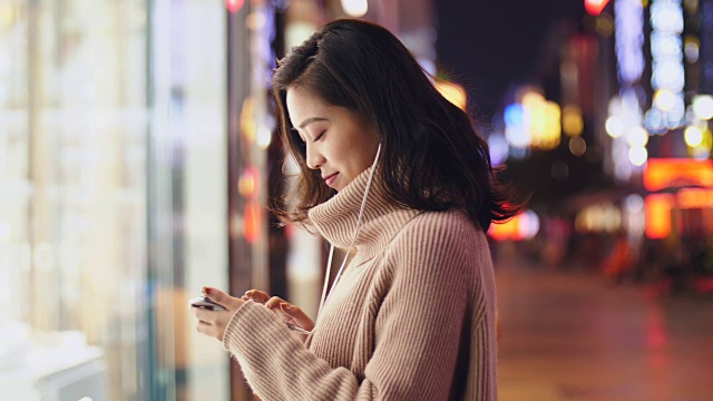 详情图-年轻的亚洲女人晚上在街上用智能手机