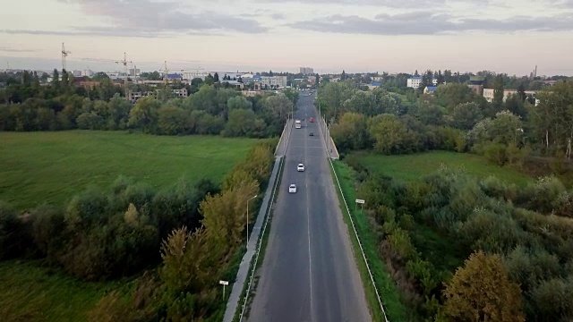 一辆卡车和其他车辆在日出时沿着道路行驶的鸟瞰图。美丽的日落在道路上的交通和长长的河流。伟大的天空。美丽的秋天。五彩缤纷的大自然