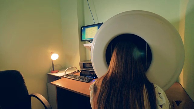 一名妇女坐在眼科检查中，她的头部位于眼科周围。4 k。