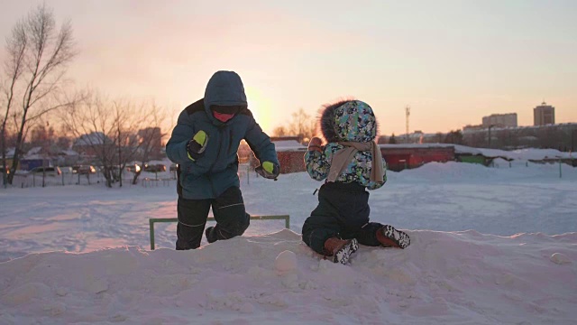 孩子们在雪山上玩耍。冬天的风景。日落时间