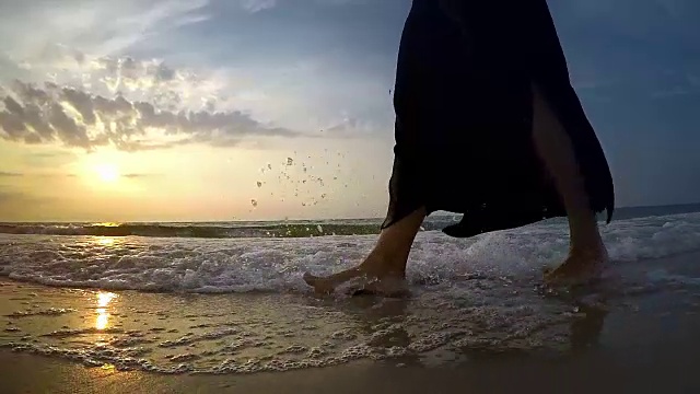 一名女子在沙滩上的海浪中行走的慢镜头