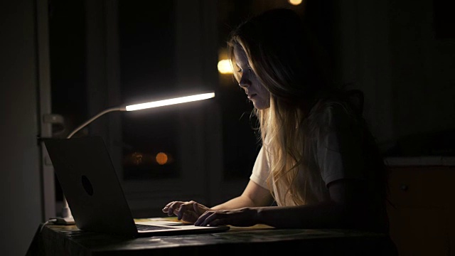女学生在暗室使用笔记本电脑进行在线教育