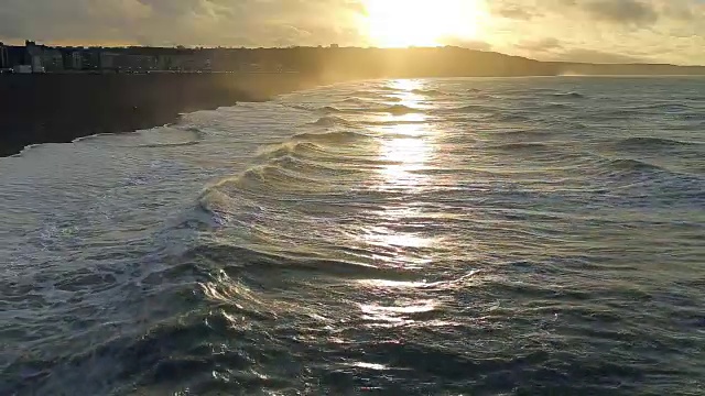 海浪的景象，诺曼底，迪耶普。多云的天气和日落在海岸。蔚蓝的海水和海滩上的泡沫。在法国北部度假。行动。实时视频，晚上。