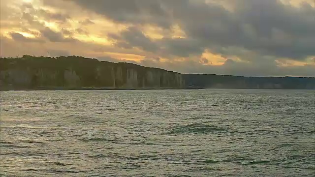 海浪的景象，诺曼底，迪耶普。多云的天气和日落在海岸。蔚蓝的海水和海滩上的泡沫。在法国北部度假。行动。实时视频，晚上。