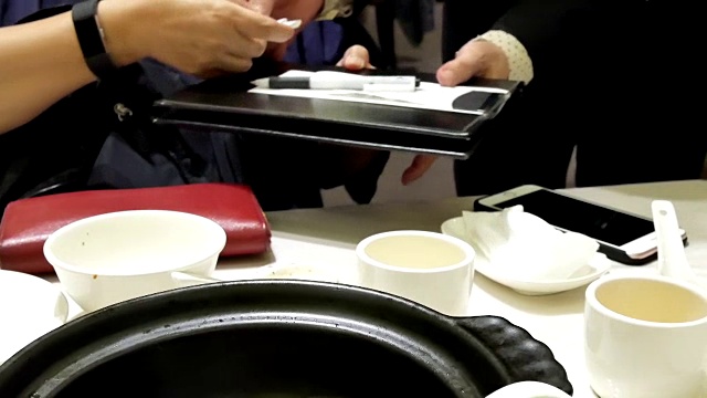 女子在中餐馆用餐后签收据的动作