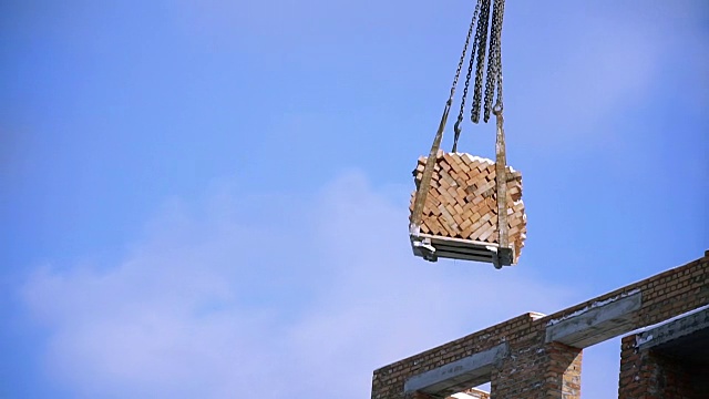 建筑。起重机将砖块移到建筑工地的上层