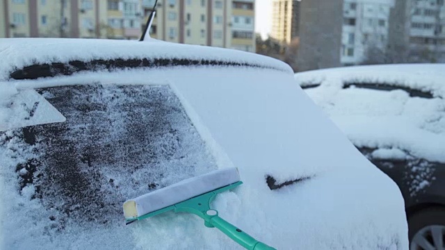 那个人正在清理车上的雪