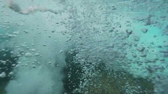 水下慢动作:强烈的管状波浪冲击海岸，使海水起泡