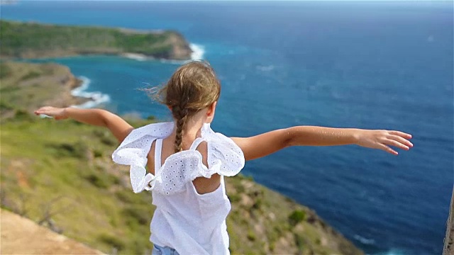 详情图-可爱的小女孩带着美丽的海湾景色像鸟儿一样飞翔