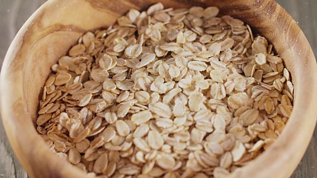 燕麦片落入木橄榄碗的特写慢镜头