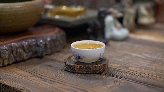 用慢动作将泡好的绿茶从玻璃茶壶中倒入白色陶瓷杯中